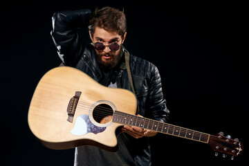 man with a guitar in his hands black leather jacket sunglasses music emotions black background