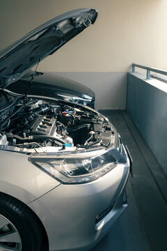 modern car with bonnet or hood open, ready to be checked or fixed at parking lot of condominium, internal combustion engine vehicle