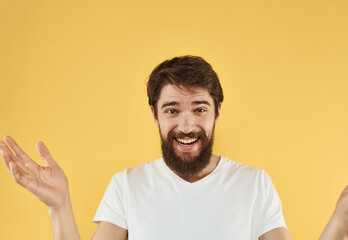 Brunette man gesturing with his hands on yellow background cropped view