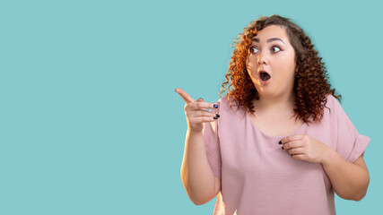 Omg woman. Gossip rumors. Body positive lifestyle. Sincere emotions. Information banner. Curious surprised plus size lady with red curly hairs pointing copy space isolated blue.