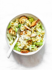 Caesar pasta salad in a bowl on a light background, top view. Delicious lunch, snack