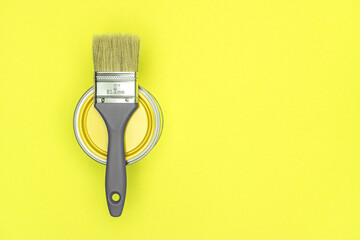 house renovation concept. metal can of yellow paint with bristle brush on yellow background