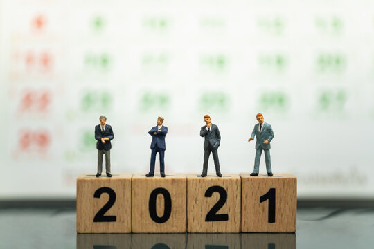 2021 Year Business and Planning Concept. Group of businessman miniature figure people standing on wooden number block with calendar as background. - Powered by Adobe