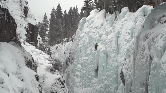 Ouray Ice Park, Colorado USA. Climber on Steep Icy Cliff Under the Bridge, Slow Motion