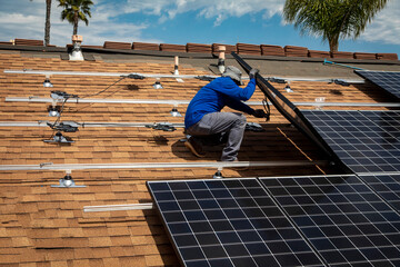 Workers installing solar panels on a tile roofon a sunny day