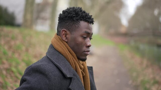 Contemplative young black man standing outside in nature park