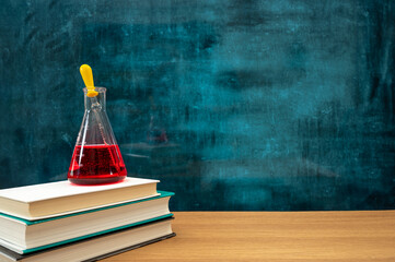 Books and scientific experiment tools on the desk. Empty blackboard. Education concept.