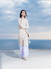 woman in light clothes by the ocean and blue sky in the background