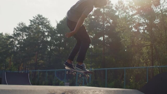 Handheld tracking shot with slowmo of young man skating and jumping over ramp but failing and falling down on ground