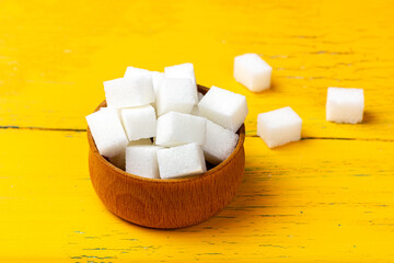 Sugar in a wooden bowl. White sweet sugar cubes.