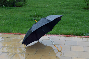 thrown black umbrella in the rain as a symbol of autumn and sadness