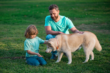 Childhood and parenthood kids concept. Happy father and son playing with pet dog outdoor. Child with her pet friend.