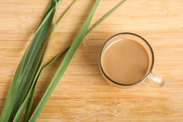 Glass cup of hot ginger tea with ginger rhizome (root) sliced isolated on wooden background.