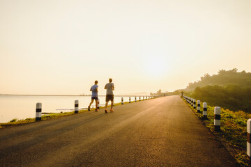 Obraz premium Rear View Of Two Man Running On Road Against Sunlight During Sunrise