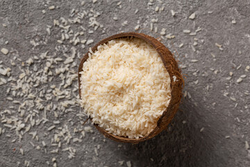 Chopped coconut with coconut flakes on a gray concrete background.