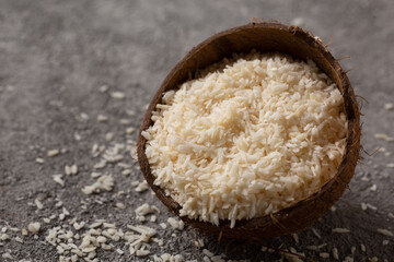 Chopped coconut with coconut flakes on a gray concrete background.
