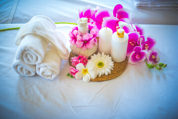Fototapeta na wymiar Towel and compress with candle and a bottle of aroma, it decorated with a flower. Spa composition on massage table