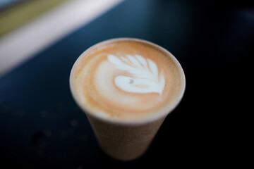 Shallow depth of field (selective focus) image with details of a decorated coffee in a paper cup.