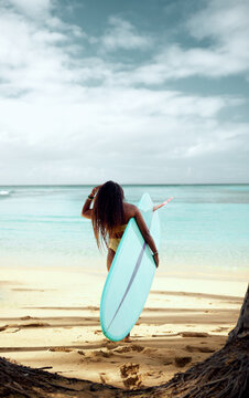 Charming Curly African-American Dark-skinned Young Woman, Professional Surfer With Long Surfboard Walk On The Beach To The Ocean