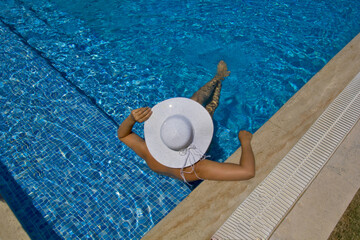Fototapeta na wymiar young woman in a white hat relaxing in the pool 