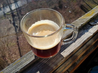 The April morning.  A cup of fragrant  coffee under sunlight. View from the window.  Background...
