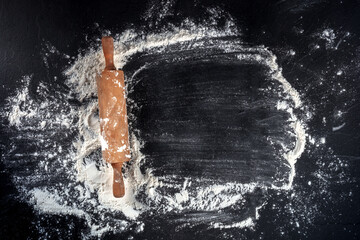 Baking background with white flour and a rolling pin, overhead shot