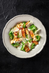 Caesar salad with chicken, green leaves and Parmesan cheese, shot from above