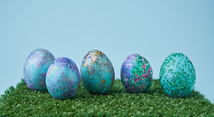 Blue painted eggs with bright shiny gliter on grass
