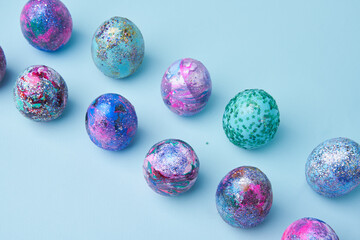 Fototapeta na wymiar Colorful painted shiny eggs on blue background.