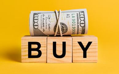 BUY with money on a yellow background. The concept of business, finance, credit, income, savings, investments, exchange, tax