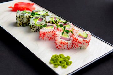 California maki sushi with caviar. Roll made of crab meat, svocado, cucumber inside. Served on a white plate.