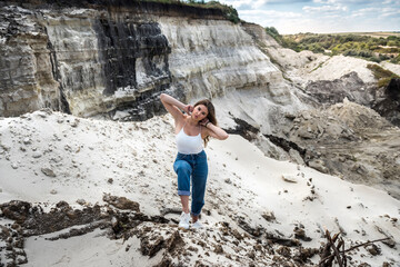 sexy beautiful young woman poses casual clothes on sand quarry