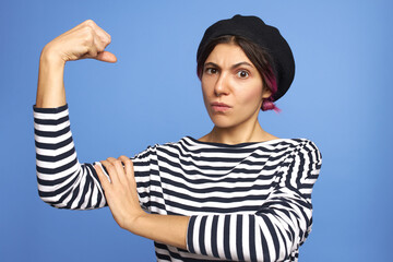 Isolated image of attractive serious young Caucasian woman wearing nose ring, striped shirt and...