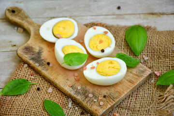 Hard boiled  organic eggs for egg fast  with fresh basil on wooden background. Ketogenic diet food