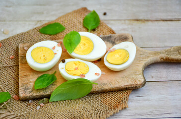 Hard boiled  organic eggs for egg fast  with fresh basil on wooden background. Ketogenic diet food
