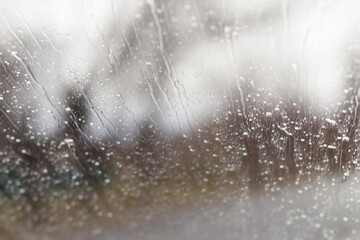 Abstract blurred background of drops and drips of rain water on the windshield glass of the car