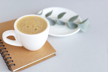 gray background with a cup of coffee, a pen and a plant. Side view.