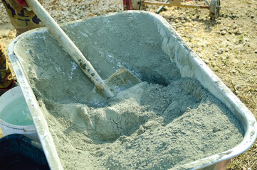 close-up - dry cement, shovel taken from a wheelbarrow for construction concrete work