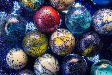 Fototapeta na wymiar Macro photography of a bunch of marbles with glitters. The marbles have different colors and sizes, creating a colorful and shiny display