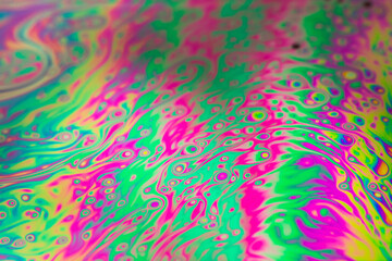 Fototapeta na wymiar The colorful close-up surface of a soap bubble with weird psychedelic background and patterns. Vivid rainbow colors in weird and strange patterns. 