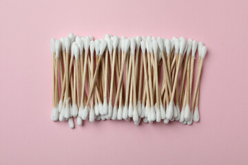 Cotton swabs on pink background, top view