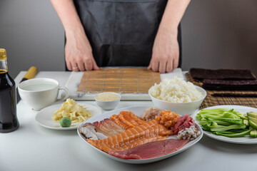 Close up of sushi chef hands preparing japanese food. Man cooking sushi at restaurant. Traditional asian seafood rolls on cutting board.