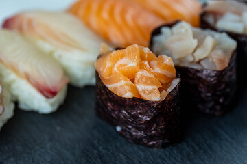 Sushi rolls prepared by professional asian chef with traditional Japanese ingredients. Salmon fish, rice, vegetables, sesame seeds.  Sushi cooking and seafood making concept