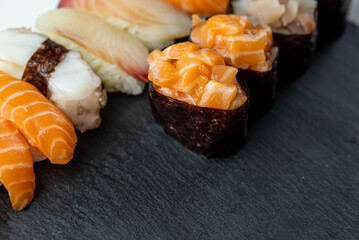 Sushi rolls prepared by professional asian chef with traditional Japanese ingredients. Salmon fish, rice, vegetables, sesame seeds.  Sushi cooking and seafood making concept