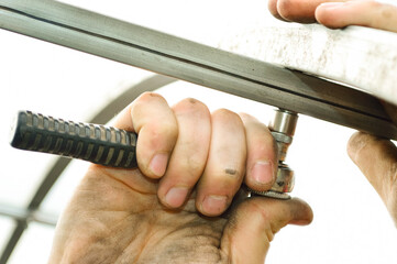 close-up - a man fixes the frame of the greenhouse with fixing bolts
