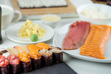 Close up of sushi chef hands preparing japanese food. Man cooking sushi at restaurant. Traditional asian seafood rolls on cutting board.