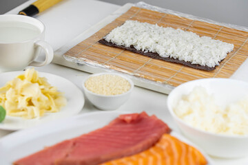 Close up of sushi chef hands preparing japanese food. Man cooking sushi at restaurant. Traditional asian seafood rolls on cutting board.