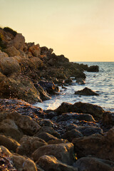 Fototapeta na wymiar Water splashing into the air over rocks at Golden Bay, Malta at sunset.