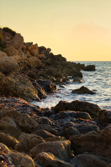 Fototapeta na wymiar Sunset at Golden Bay, Malta with wate splashing over the rocks on the beach.