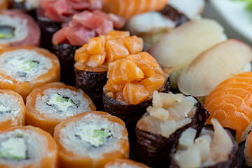Sushi rolls prepared by professional asian chef with traditional Japanese ingredients. Salmon fish, rice, vegetables, sesame seeds.  Sushi cooking and seafood making concept